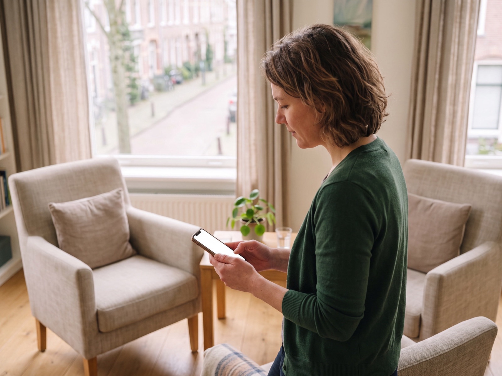 Coach staat in haar praktijkruimte en typt een bericht op haar telefoon