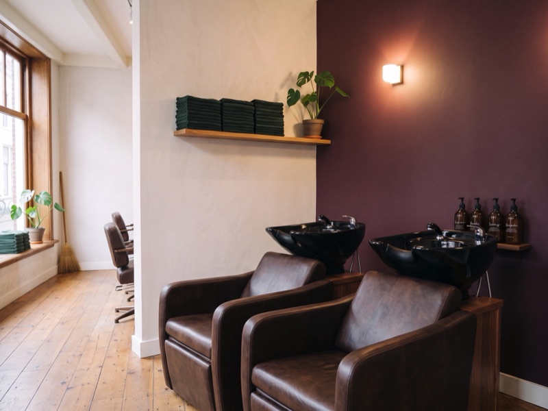 De washoek met twee zwarte wasbakken en twee leren stoelen